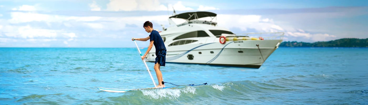 Guest paddleboarding beside the yacht.